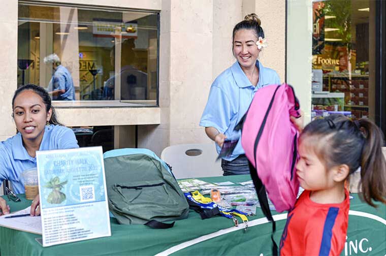 Hale Opio hands out backpack with school supplies - Charity Walk 2022