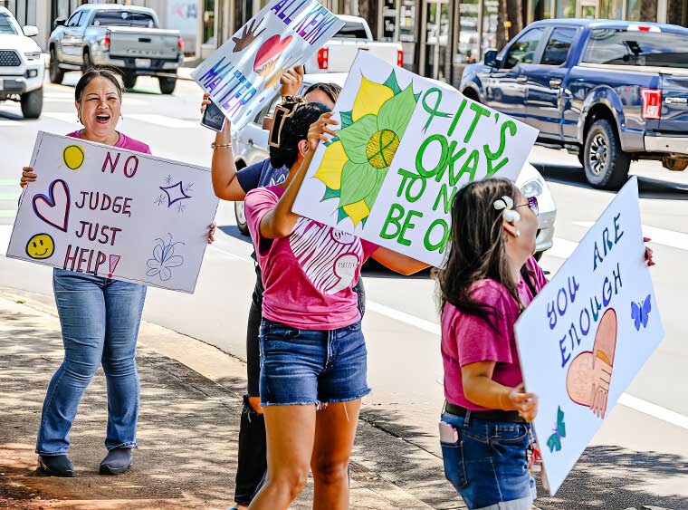 People standing on the sidewalk holding signs to bring attention to suicide prevention - Hale Opio Kauai. Photo credits: Dennis Fujimoto - The Garden Island